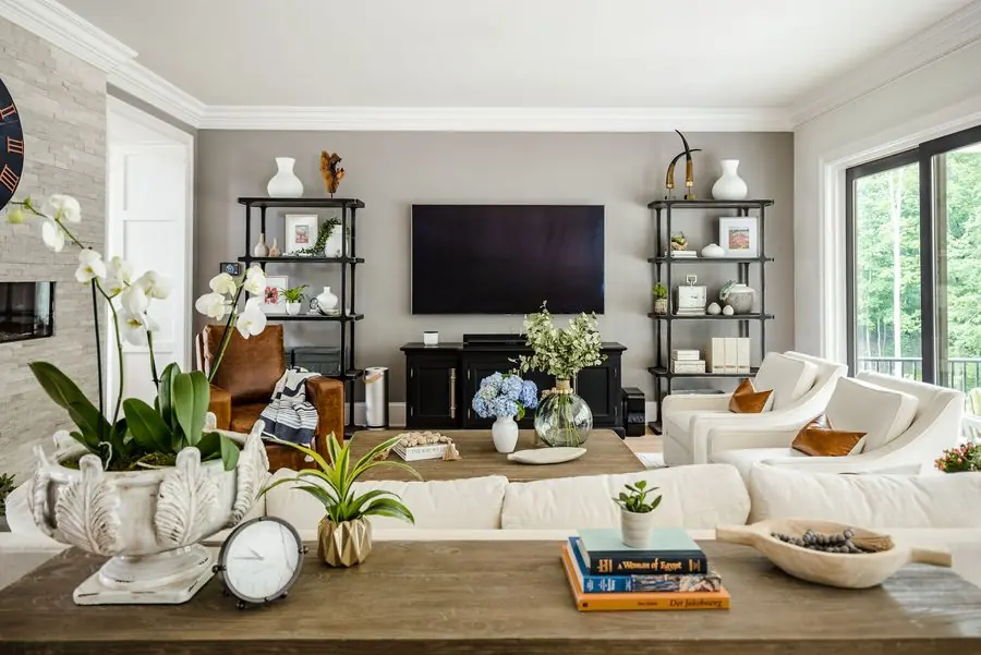 Sitting room with open shelving, layered neutral upholstery, and floor-to-ceiling glass