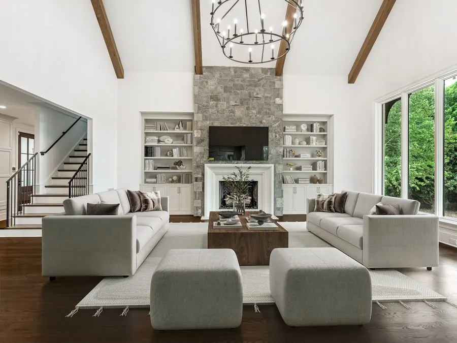 Great room in an Everett Custom Homes project with exposed timber trusses, a stone fireplace, and built-in shelving