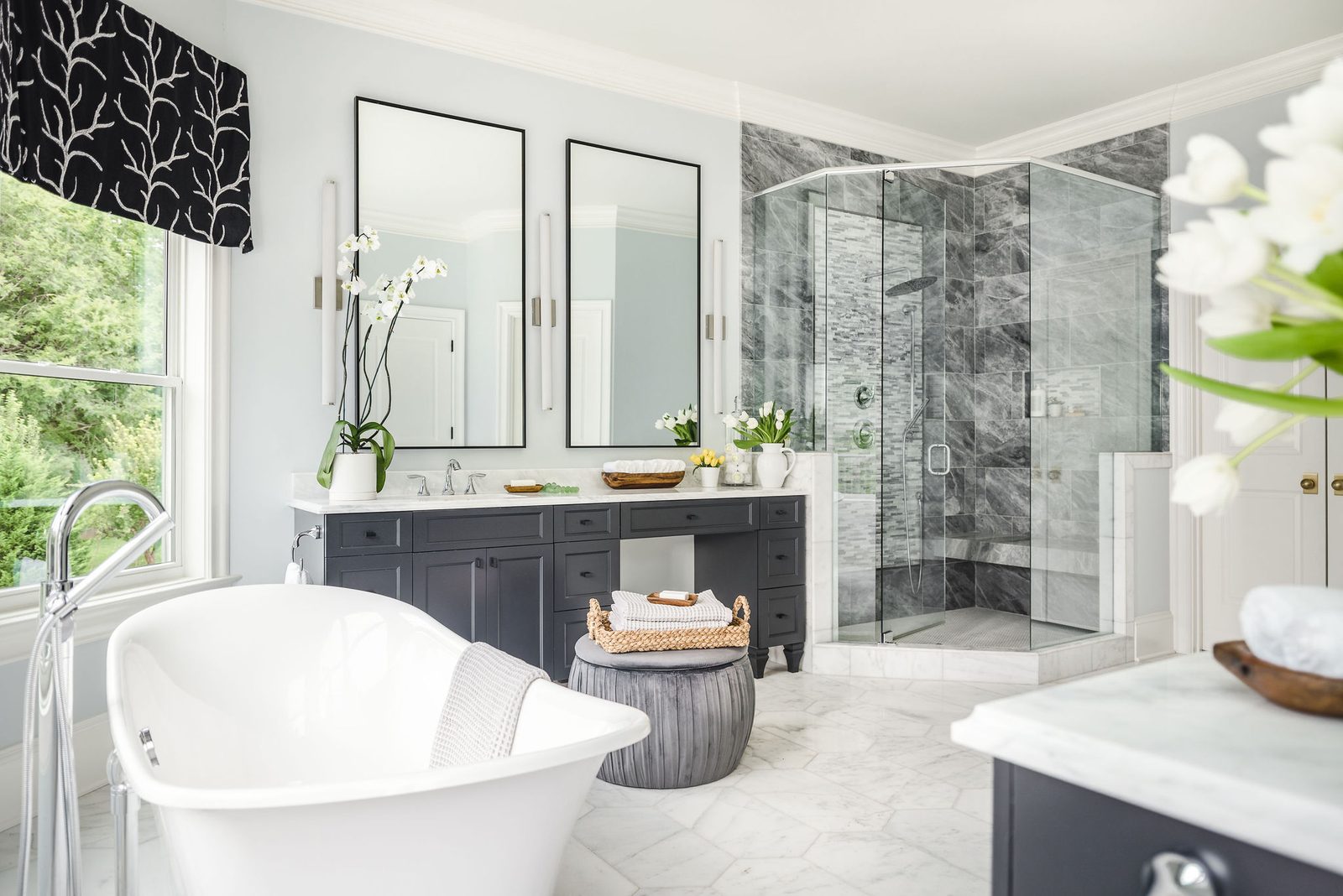 A finished primary bathroom in an Everett Custom Homes build, with a marble-tiled shower, freestanding tub, and dual vanity.